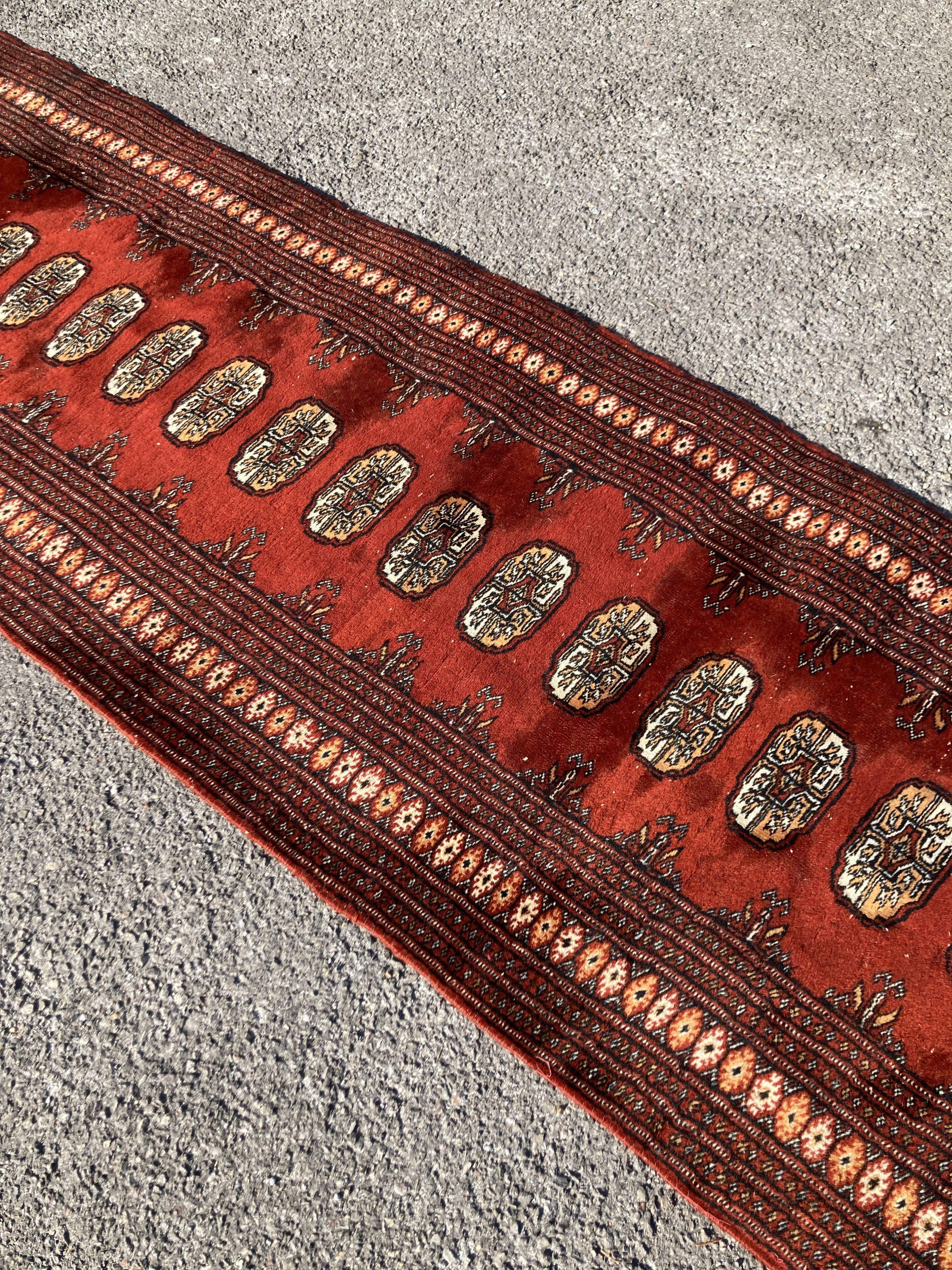 A Bokhara red ground runner with multi medallion field, 326 x 80cm